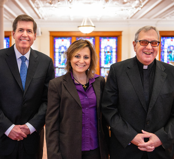 A man in commencement regalia holds up his degree with Gonzaga University written on it